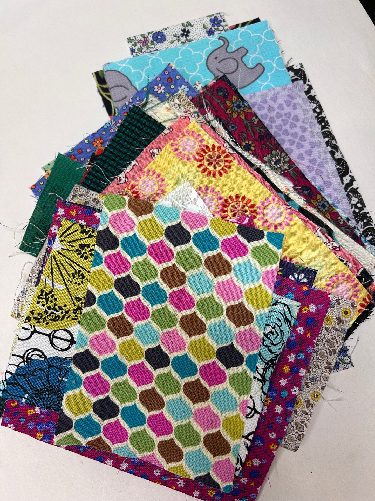 Collection of colorful fabric scraps  with various patterns on a white background